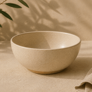 Bol Horizon en céramique écru naturel de 50 cl sur une table aux tons beige sable.